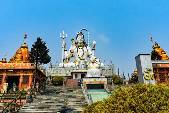 Giant Lord Shiva statue at The Char Dham temple complex in Namchi, colorful architecture under clear blue sky.