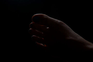 Low-Key Detailaufnahme eines weiblichen Fu&szlig;es im dunklen Licht. &Auml;sthetische Silhouette mit Fokus auf Zehen, Form und Schatten &ndash; geeignet f&uuml;r Themen wie K&ouml;rper&auml;sthetik, Pflege und sinnliche Fotografie.