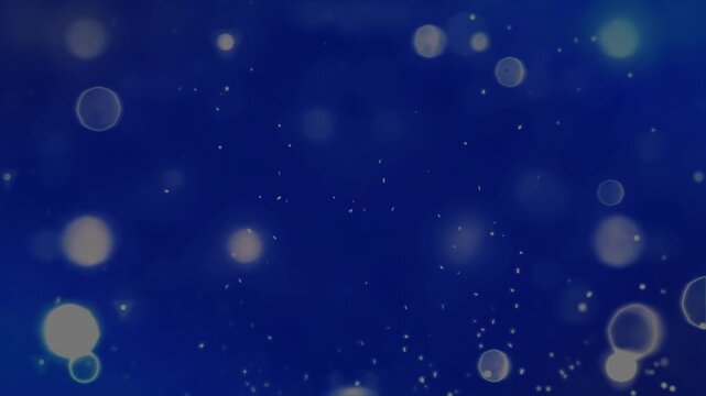 Abstract deep blue background featuring soft golden bokeh lights and floating dust particles for festive holiday or elegant corporate design.
