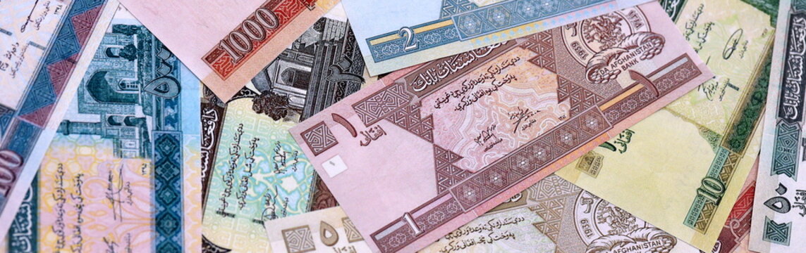 Afghan afghani money bills pile on table. Afghanistan banknotes of AFN currency close up.