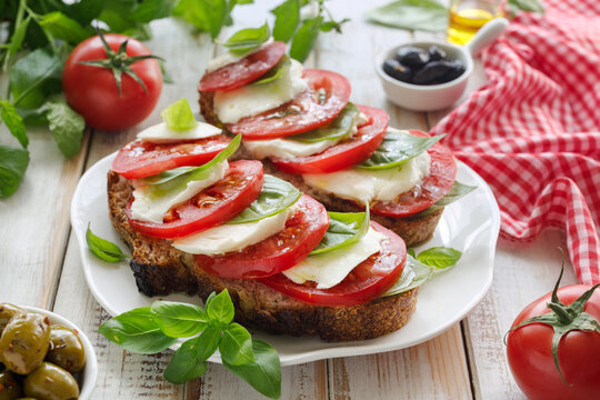 Bruschetta with tomatoes and mozzarella, caprese salad on a white plate, close-up