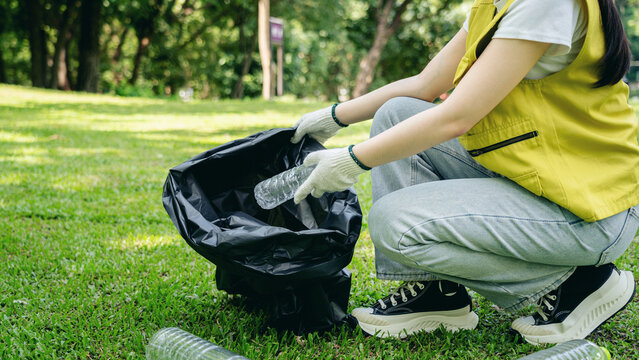 Community volunteer collecting plastic bottles recycling park environment cleanup promoting global sustainability healthy planet action outdoor