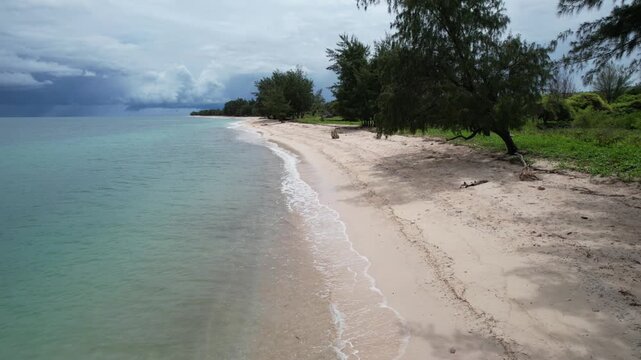 a beach with turquoise water decorated with white sand full of crushed coral taken using a drone