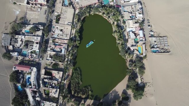 Cinematic drone reveal of Ica city skyline from the massive sand dunes of Huacachina oasis