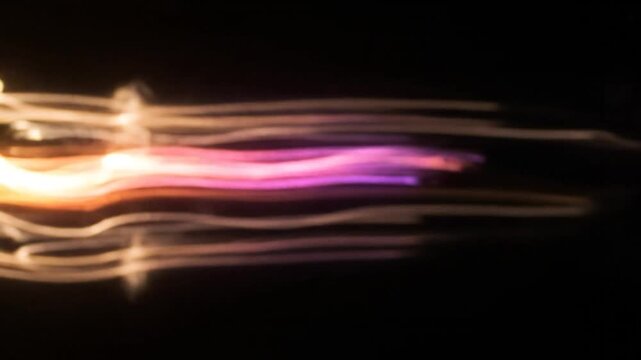 Abstract image features blurred golden streaks on a black background, evoking movement