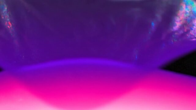 Abstract image with a gradient of purple over a black speckled texture