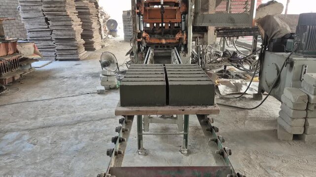Professional RAW eye level medium shot of eco-friendly cement bricks on a conveyor belt production line in Bangladesh, 4K UHD 30fps.