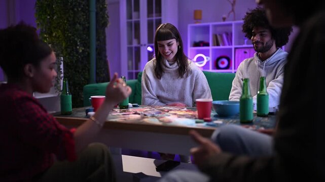 Multiracial friends laughing and talking while playing a board game at home during a social gathering at night