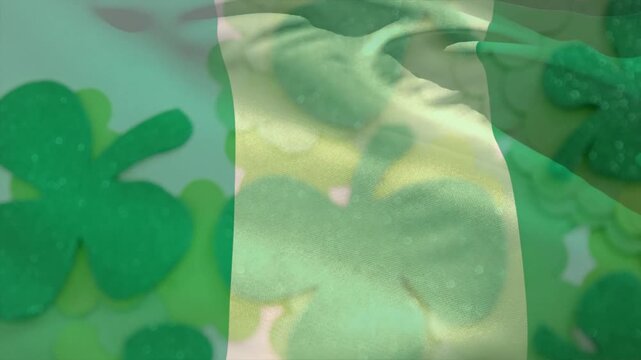 Hand tugging green-striped fabric, waving and revealing glitter clover layers for craft display