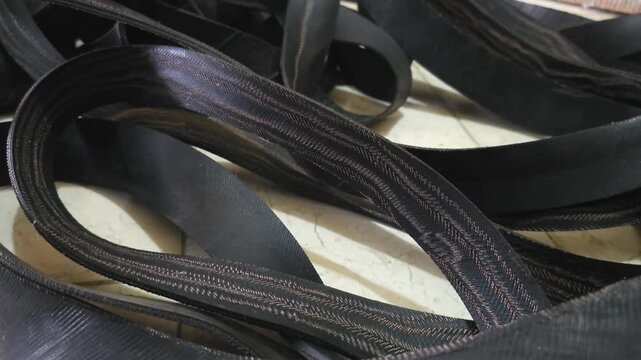 Close up of pile of black rubber strips and textured herringbone elastic webbing bands