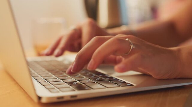 Focus on fingers entering reservation details. Closeup of hands typing at desk with warm lighting. Individuals entering reservation information on computer in cozy hotel environment