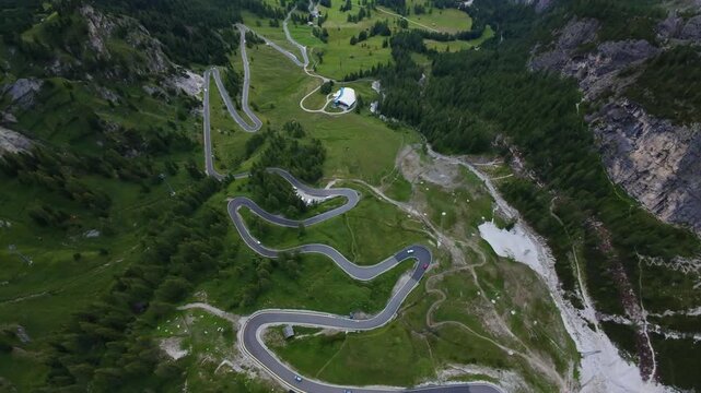 Aerial View Mountain Switchbacks Dolomites, Panoramic Vantage Shows Winding Ribbon Of Asphalt, Small Refuge And Steep Green Slopes, Dramatic Perspective Over Cliffs And Meadows, Exhilarating Highland