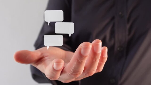 Close-up of a businesswoman's hand holding an animation of several speech bubbles, in the form of a chat.