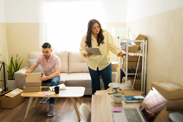 Fototapeta premium Partners managing small business orders from home, packing boxes for e-commerce side hustle delivery