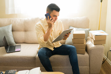 Fototapeta premium Latin man working remotely, handling shipments and customer service for online business from home office