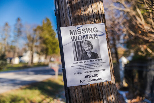 Missing woman reward poster attached to wooden utility pole in suburban neighborhood USA