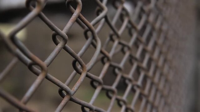 Rusty metal chain link fence with grid pattern viewed from a close-up angle outdoors