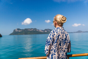 Fototapeta premium Middle-aged woman standing on cruise ship deck and looking at tropical islands in Ang Thong Marine Park Thailand during sea journey