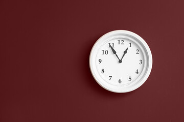 Stylish clock hanging on red wall