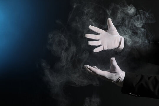 Male magician's hands with smoke on dark background