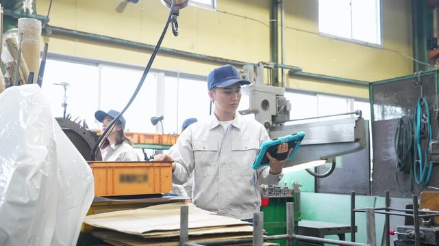 工場で作業するタブレットを持って作業員グループ