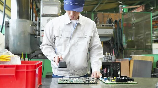 工場でハンディターミナルを使って製品を検査する男性作業員