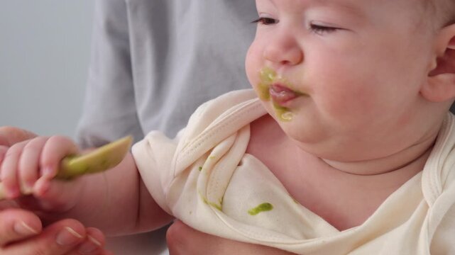  A baby picking and eating food from a sectioned plate with her fingers. The concept of weaning is based on the principle of "child-choosing food," independent feeding, healthy breakfast, and fine mot