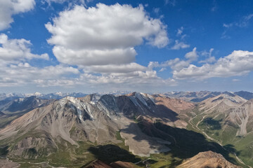 Fototapeta premium Wide view from Satpayev Peak showing massive clouds over the rugged mountain peaks of the Almaty region.
