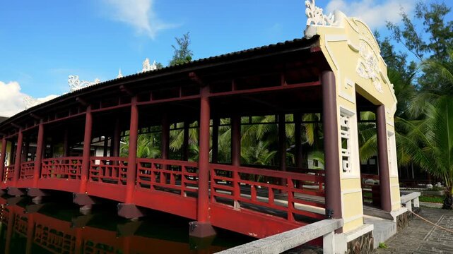 A serene covered wooden bridge at Lang Co Resort, featuring traditional Vietnamese architecture with ornate yellow gables and dragon motifs.