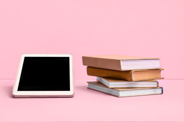 Fototapeta premium Books with modern tablet computer on pink background. Concept of evolution