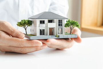 家の模型を持つ女性の手　不動産やマイホームのイメージ素材