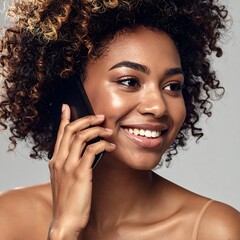 A woman with curly hair talking on her phone with a smile