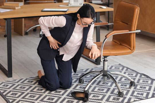 Young businesswoman with severe abdominal pain fell down from chair in office