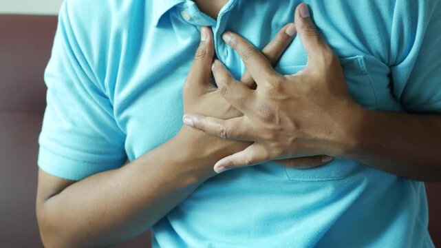 Man clutching chest in pain experiencing heart attack or chest pain symptoms