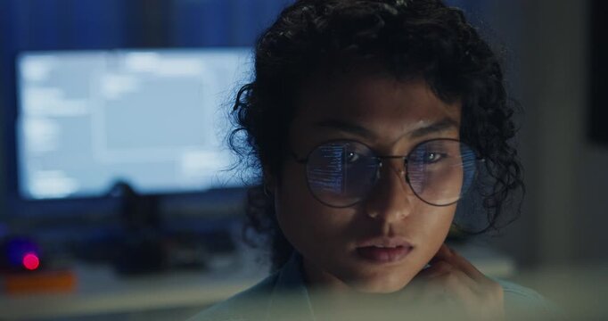 Close-up Black female programmer with code reflection in glasses working late in home office at night. Cybersecurity, AI algorithm, Network security, software developer, serious face, burnout concept.
