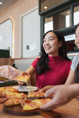 Young woman enjoying pizza with friends at restaurant