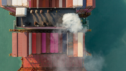 Aerial view container cargo ship with smoke exhaust gas emissions, Container cargo ship diesel engine exhaust gas combustion, Smoke exhaust gas emissions carbondioxide container cargo  ship. © Kalyakan
