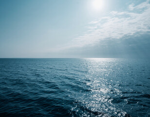 Calm sea surface reflecting sunlight,, vast blue ocean, atmospheric perspective, tranquil marine scene, coastal landscape.