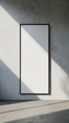 Tall blank frame mounted on light grey wall with shadows
