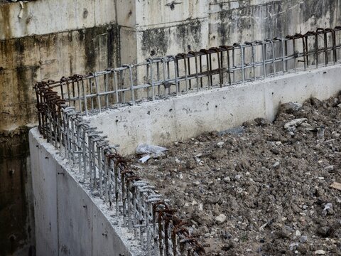 A concrete wall with a metal fence on top of it. The fence is rusted and has a lot of holes