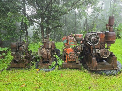 Three old engines are sitting in a grassy field