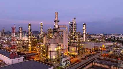 Fototapeta premium Aerial view oil and gas industrial refinery at twilight, Oil refinery and Petrochemical plant pipeline steel, Refinery factory oil storage tank and pipeline steel at night.