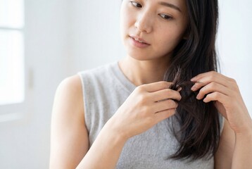 Fototapeta premium Young asian woman examining split ends of her long dark hair