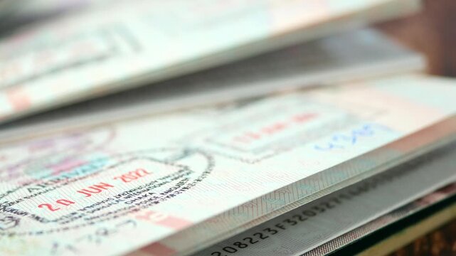 Macro view of several passports stacked together showing travel visa stamps and arrival dates