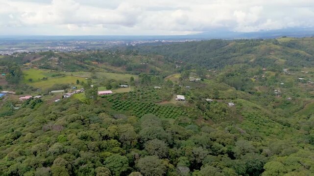 An aerial shot showcasing green hills and farmhouses under a cloudy sky in Popay&aacute;n, Cauca, Colombia.