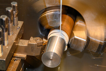 Precision lathe performing a final finish cut on a steel shaft using  liquid coolant for thermal...