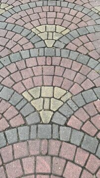 Elegant Fan-Patterned cobblestone walkway in earthy red, gray, and tan hues. Vertical shot, walking forward. 4k 60 Fps