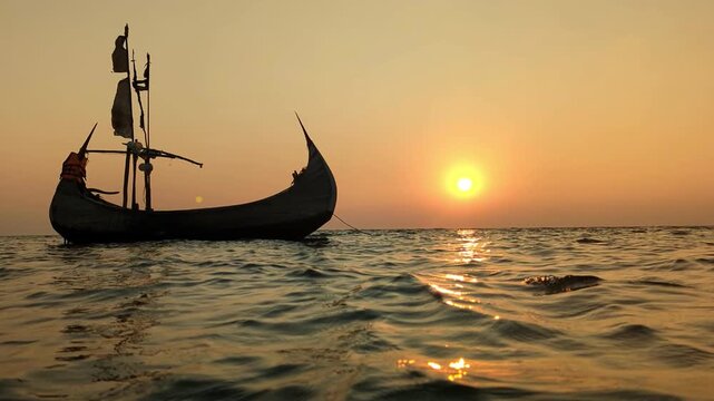 ​Traditional Wooden Vessel Sailing on Calm Sea Waves During Vibrant Tropical Sunset at cox's bazar