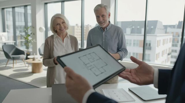 Real estate agent senior client couple review modern digital floor plan on tablet together