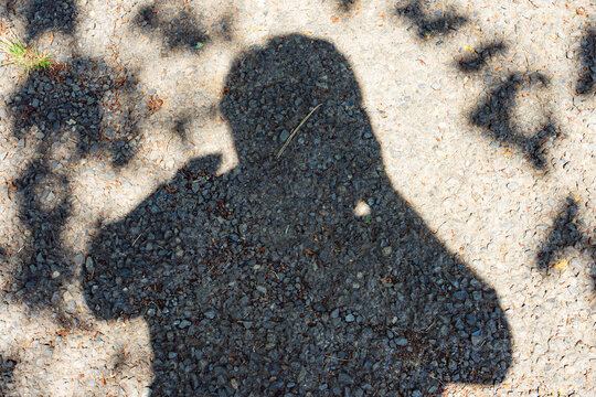 Shadow of a Person on Textured Asphalt Ground